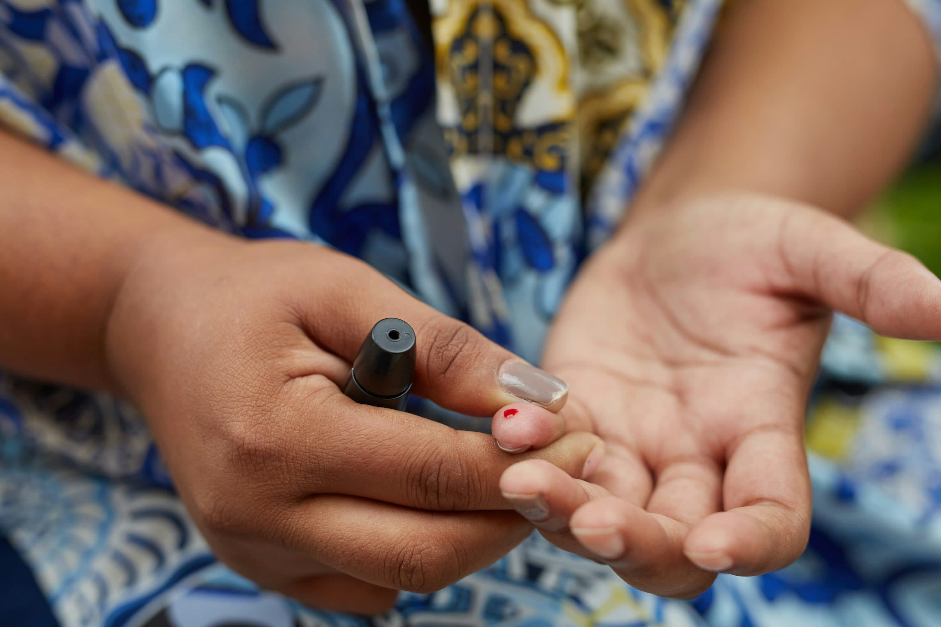 Hands holding a lancing device after a finger-prick blood glucose test