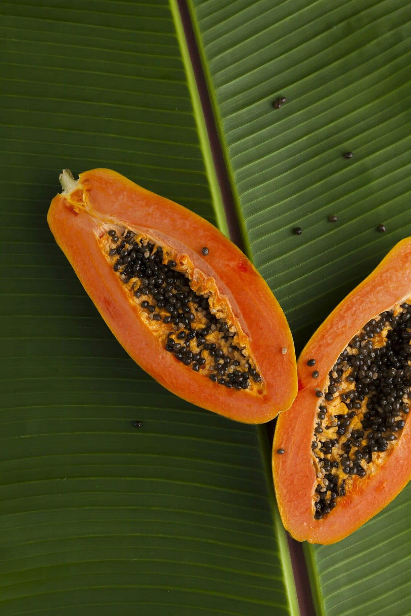 A ripe pawpaw cut in half on a banana leaf
