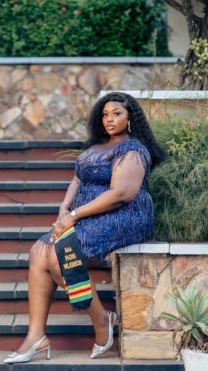 Dora Wilkinson seated on garden steps in a blue sequinned dress and a kente stole